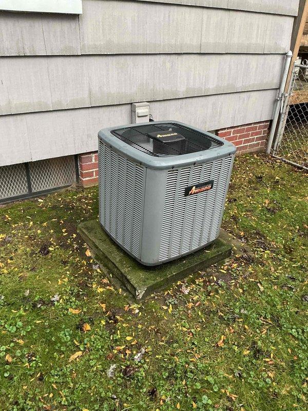 Performed seasonal cooling maintenance on an Amana split-system condenser, including inspection of the electrical compartment, contactor, run capacitor, and wiring connections, as well as the CoreSense compressor diagnostics module. Checked the unit's overall condition, noting moss and algae buildup on the concrete pad and minor corrosion on the base bracket, and confirmed the system is operating properly.