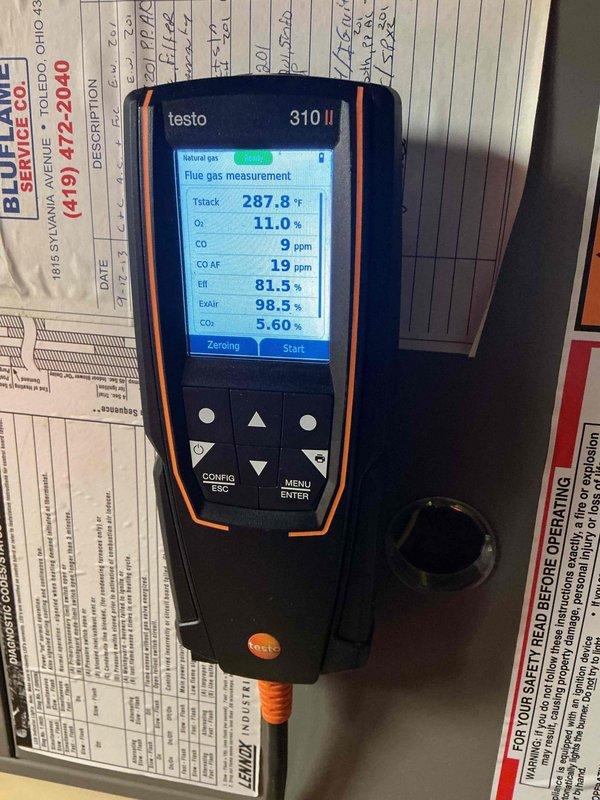 Performed a seasonal tune-up on an 18-year-old Lennox gas furnace with an attached Aprilaire Model 2200 media air cleaner, accessed via ladder in the attic. Conducted a combustion analysis with a Testo 310 II flue gas analyzer on natural gas, recording a stack temperature of 287.8°F, 11.0% O2, 5.60% CO2, 9 ppm CO (19 ppm air-free), and 81.5% efficiency with 98.5% excess air, confirming safe CO levels and operation within acceptable range.