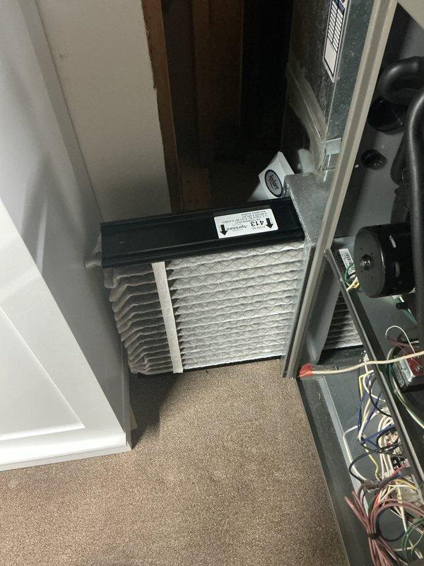 Performed seasonal maintenance on a 5-year-old gas furnace, inspecting the cabinet, internal wiring, blower motor, and condensate tubing, and checking the pleated return air filter, which showed dust loading and discoloration along its edges and should be replaced on a regular schedule. Verified the drain line on the bypass humidifier is routed correctly and free of obstruction. Observed visible mold or mildew staining on pillows stored near the equipment in a damp, cluttered utility area and recommended relocating stored items away from the furnace and humidifier, improving airflow and moisture control, and clearing the equipment area to maintain safe clearances.