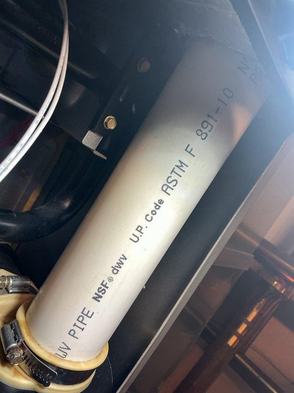 Performed a seasonal tune-up on a 2-year-old gas furnace, inspecting the cabinet interior, condensate drain line, and electrical connections. Found significant rust and corrosion on the galvanized cabinet floor beneath the condensate drain hose and fitting, indicating a possible past or ongoing leak at the drain connection; recommend monitoring and further evaluation. Condensate PVC drain piping and rubber coupling were secure and free of cracking or damage, and the 16x25x1 air filter was verified in place.