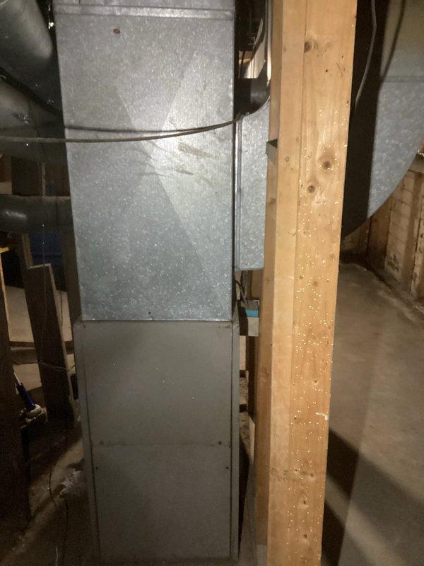 Performed an on-site evaluation for replacement of an existing Moncrief upright gas furnace located in an unfinished basement utility space. Inspected the furnace cabinet, supply plenum, galvanized ductwork, and flexible duct connections, documenting equipment condition and installation clearances with photographs. Existing unit shows age-related dust accumulation with no visible frost or major corrosion, and the documented findings were used to determine replacement scope and sizing.
