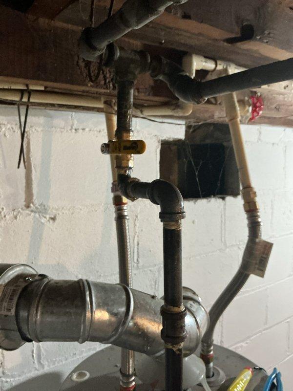 Responded to a reported gas leak with gas service shut off and leak source unknown, and inspected the gas piping at the water heater, including the black iron supply line, ball valve, and flexible appliance connectors, along with accessible gas piping in the basement floor joist area. Leak location was not identified on the initial visit, so a follow-up appointment is required to return and complete an air pressure test of the gas piping system to isolate the leak before restoring service.