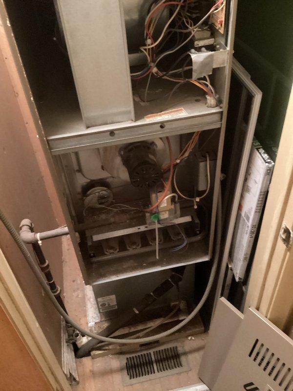 Performed an on-site evaluation of the existing gas furnace and air handler for full system replacement, inspecting the control board, wiring harness, blower assembly, burner section, igniter, pressure switch, and condensate drain components. Documented heavy dust and debris accumulation, loose insulation near the motor, taped wiring repairs, and a 10x20x1 return filter, with photos taken to support the replacement recommendation for both the furnace and AC.
