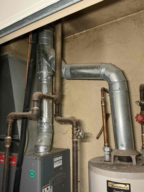 Responded to complaint of furnace short cycling and reduced heating efficiency; inspected the Armstrong Air gas furnace and observed the burner assembly firing with a stable blue flame across all burners. Evaluated the venting and combustion components, including the galvanized flue connection to the water heater vent, as part of the short-cycling diagnosis, and noted dirty burner compartment with debris and residue. Furnace was left operating and cycling through the heat call.