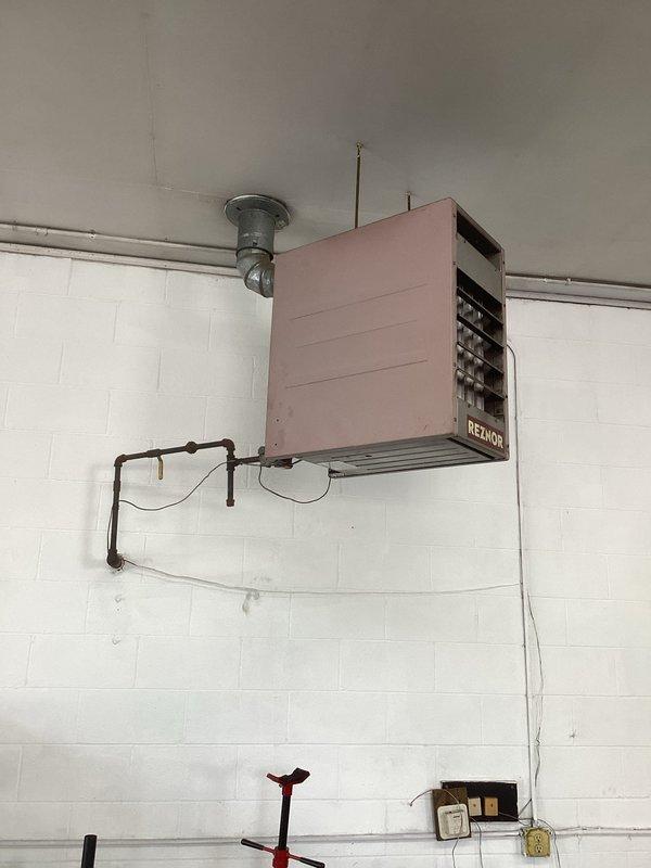 Inspected four suspended Reznor gas-fired unit heaters in a garage/shop space and documented existing conditions, including cabinet wear, black iron gas piping with surface rust, galvanized flue venting, threaded-rod hangers, and flexible electrical connections to ceiling junction boxes. Prepared an estimate to replace all four units, including gas line reconnection, flue and venting, electrical connections, and hanger support.