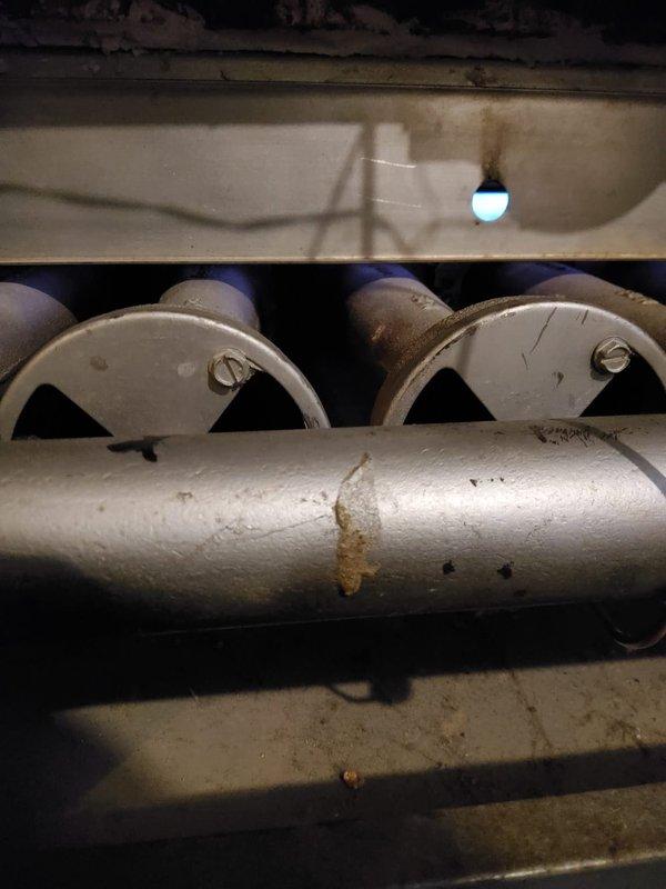 Completed boiler tune-up service that was previously rescheduled. Inspected burner tubes and heating assembly, noting minor corrosion and rust formation on main horizontal pipe. Visual inspection confirmed operational status of ignition system with functioning indicator light.