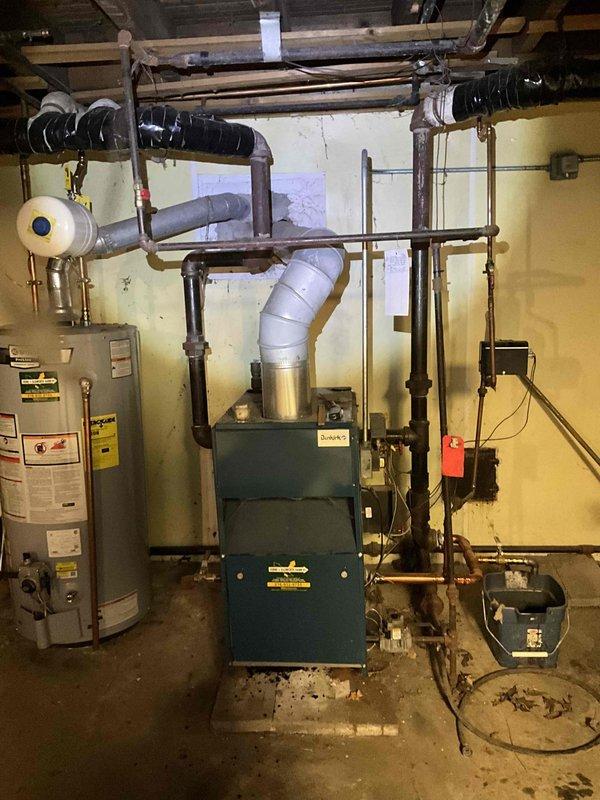 Performed diagnostic assessment on 15-year-old furnace system in basement mechanical room. Identified aging components and evaluated existing ventilation setup including PVC exhaust and black insulated ductwork. Recommended replacement options due to unit age and efficiency concerns.