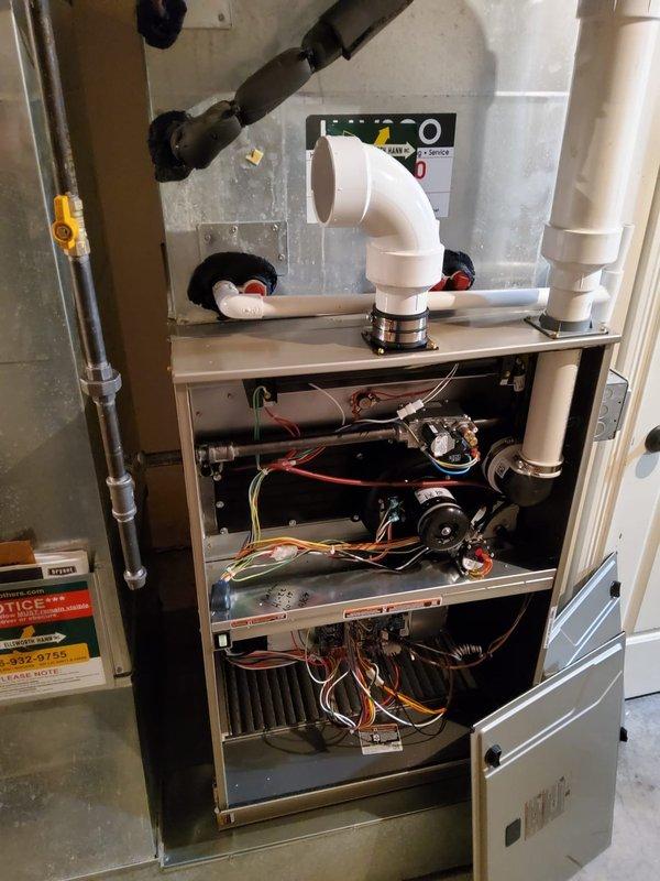 Successfully installed new furnace with integrated thermostat in residential utility area, including addition of 24" EZ Flex filter box beneath unit. Retained existing airflow base and 3" PVC single-pipe venting system for proper exhaust ventilation.