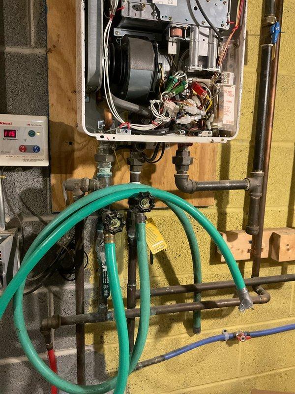 Performed diagnostic assessment on customer's tankless water heater system due to reported 2+ minute delay for hot water to reach kitchen sink. Inspected internal components of wall-mounted tankless unit and examined associated plumbing configuration. Identified circulation pump installed on return line that requires adjustment to improve hot water delivery time. Completed whole home plumbing assessment as part of service visit.