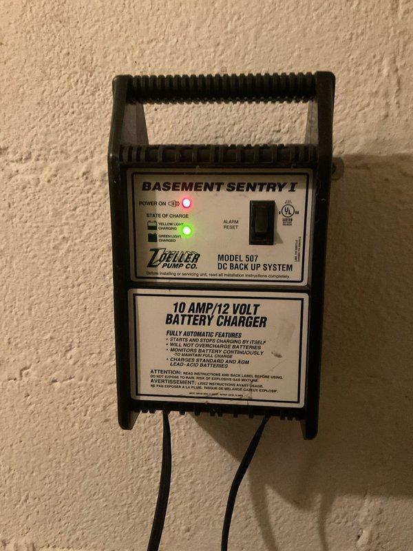 Conducted assessment of backup sump pump system at client Derek's property. Inspected Zoeller Pump Co. Model 507 "BASEMENT SENTRY I" DC Back Up System (10AMP/12VOLT) and verified proper operation with both power and charging indicator lights functioning. Examined the dual automotive batteries in plastic holders connected to the system, noting proper terminal connections and secure mounting.