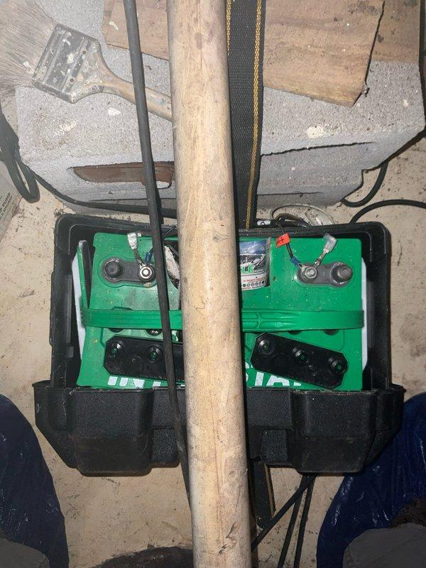 Conducted assessment of backup sump pump system at client Derek's property. Inspected Zoeller Pump Co. Model 507 "BASEMENT SENTRY I" DC Back Up System (10AMP/12VOLT) and verified proper operation with both power and charging indicator lights functioning. Examined the dual automotive batteries in plastic holders connected to the system, noting proper terminal connections and secure mounting.
