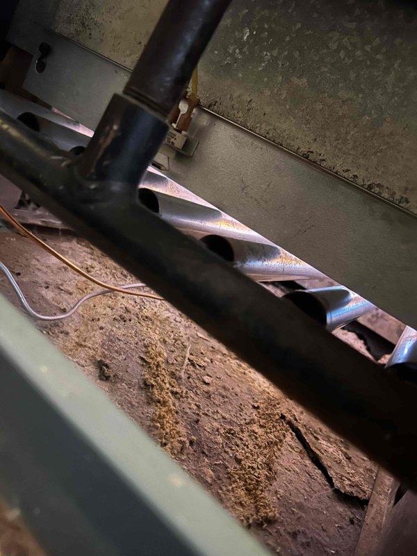 Performed scheduled boiler tune-up service. Discovered significant moisture damage and deterioration on heat exchanger components, with visible mold/rust accumulation at pipe connections. Inspected mechanical components including auger assembly which showed dirt buildup and wear.