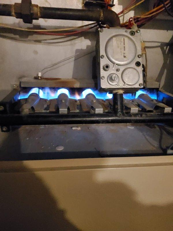 Responded to a no-heat service call for a 30-year-old gas furnace. Upon inspection, identified and resolved issues with the burner assembly, ensuring proper flame distribution and combustion as evidenced by the even blue flames across all burners. System was successfully restored to normal operation with appropriate gas valve functionality verified.