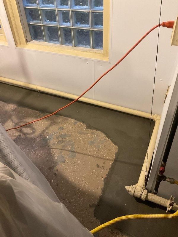 Responded to service call for intermittent boiler operation. Diagnosed leaking return pipe connection. Repaired pipe leak and verified proper system operation with heat set at 69°F. Documentation shows evidence of previous water damage on concrete floor near plumbing connections.