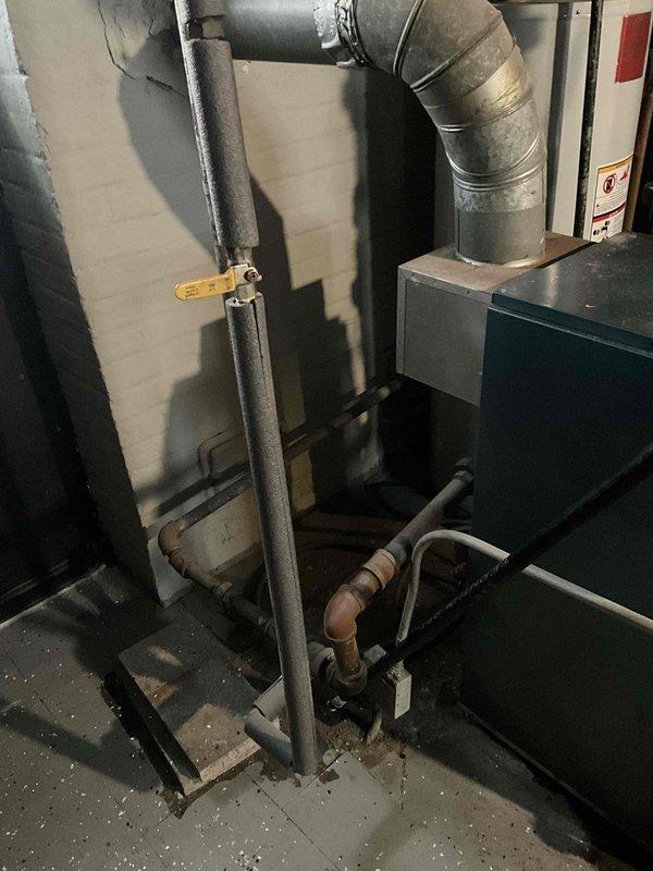 Inspected aging boiler system that was previously serviced in November and reported as non-functional again. Visual examination revealed an older blue-green heating unit with signs of wear and connected galvanized exhaust ducting. Evaluated control components, burner assembly, valves, and various copper/metal pipe connections for proper operation prior to anticipated storm conditions.