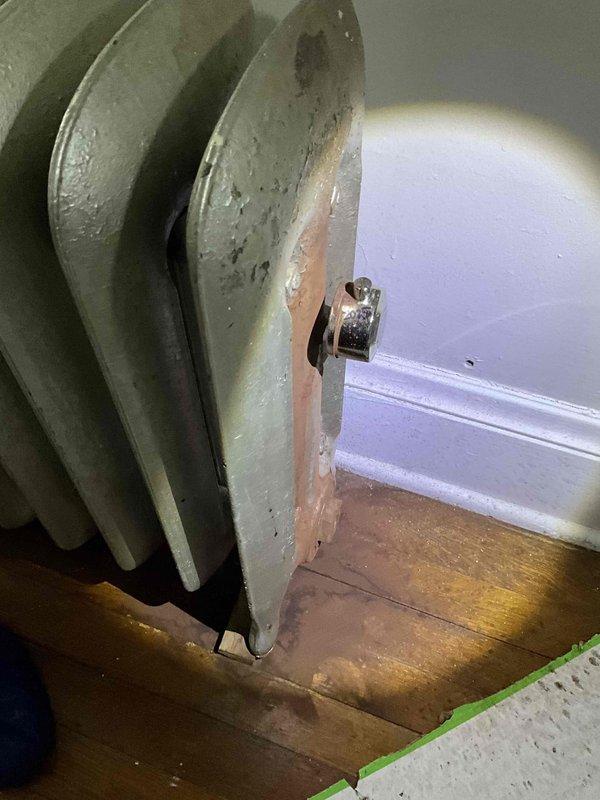 Conducted comprehensive inspection of aging steam heating system, including cast iron radiators showing surface deterioration and rust in residential unit. Examined blue boiler unit mounted on concrete platform with associated piping infrastructure and ventilation components. Documented system condition with photos for assessment and estimate purposes.