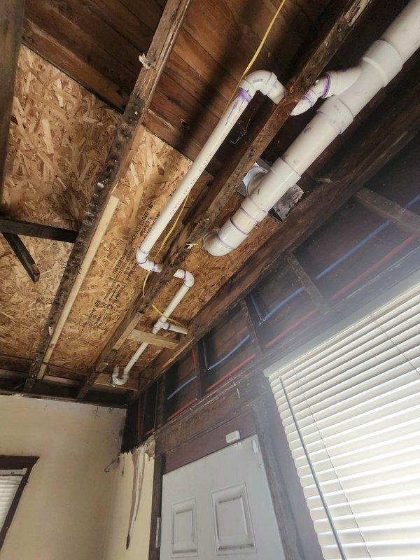 Conducted inspection of property's plumbing system to prepare quote for waterline and drain replacement. Examined exposed PVC drainage system in basement/crawl space area with dirt floor and concrete walls. Also assessed ceiling-mounted PVC plumbing infrastructure with multiple connection points and joints that showed evidence of purple primer application. Photos documented current installation to support detailed replacement quote.