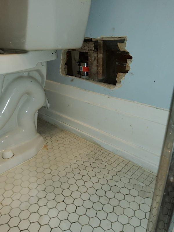 Accessed bathroom plumbing system by opening wall adjacent to toilet to expose leaking 2" cast iron pipe. Removed damaged section and replaced with new PVC piping, ensuring proper connections and sealing. Completed functional testing to verify repair eliminated the leak.