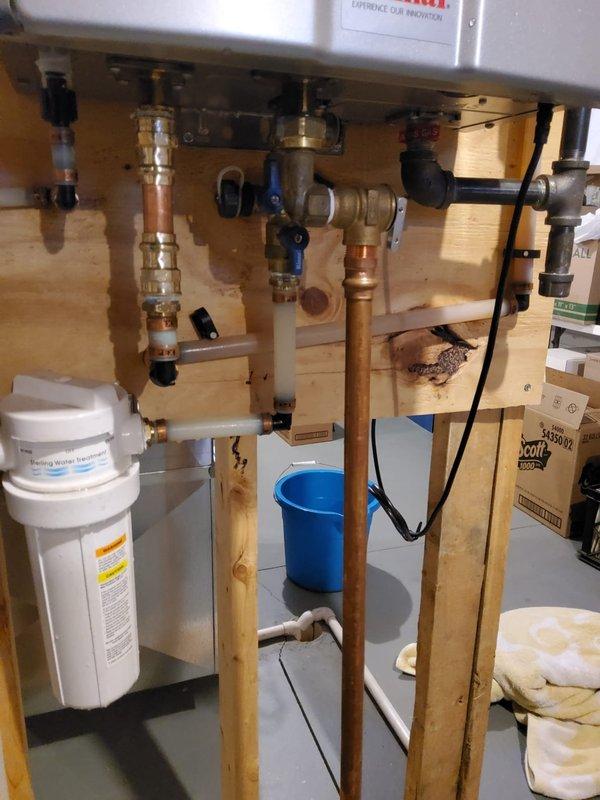 Responded to a warranty service call for a tankless water heater system with ongoing leakage issues. Previously replaced pressure relief valve on January 29th, but inspection revealed current leak is unrelated to that repair. System includes copper and PVC piping assembly with multiple control valves and a water filtration unit. Customer advised that additional repairs would be chargeable as the current issue is separate from warranty work.