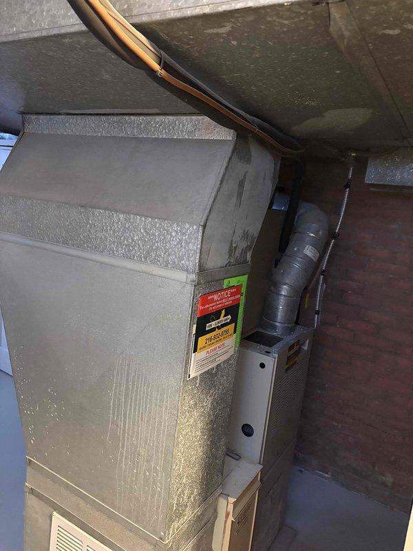 Conducted furnace replacement estimate for 25-year-old unit showing significant wear and dust accumulation. Inspected existing system including ductwork configuration and connections in basement utility area. Documented current installation with photos to develop appropriate replacement options for this aging residential heating system.