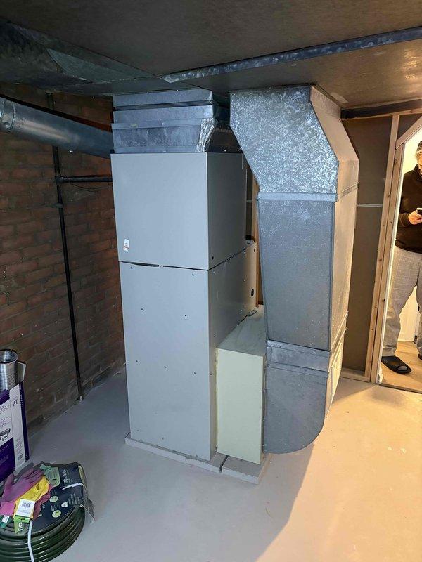 Conducted furnace replacement estimate for 25-year-old unit showing significant wear and dust accumulation. Inspected existing system including ductwork configuration and connections in basement utility area. Documented current installation with photos to develop appropriate replacement options for this aging residential heating system.
