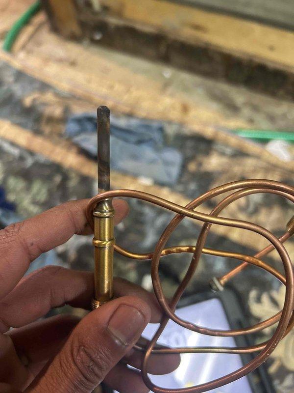 Inspected existing boiler system and identified faulty thermocouple component. Removed damaged assembly with coiled copper tubing and replaced with new brass thermocouple to restore proper temperature sensing functionality. System tested and confirmed operational.