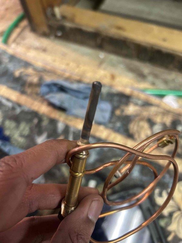 Inspected existing boiler system and identified faulty thermocouple component. Removed damaged assembly with coiled copper tubing and replaced with new brass thermocouple to restore proper temperature sensing functionality. System tested and confirmed operational.