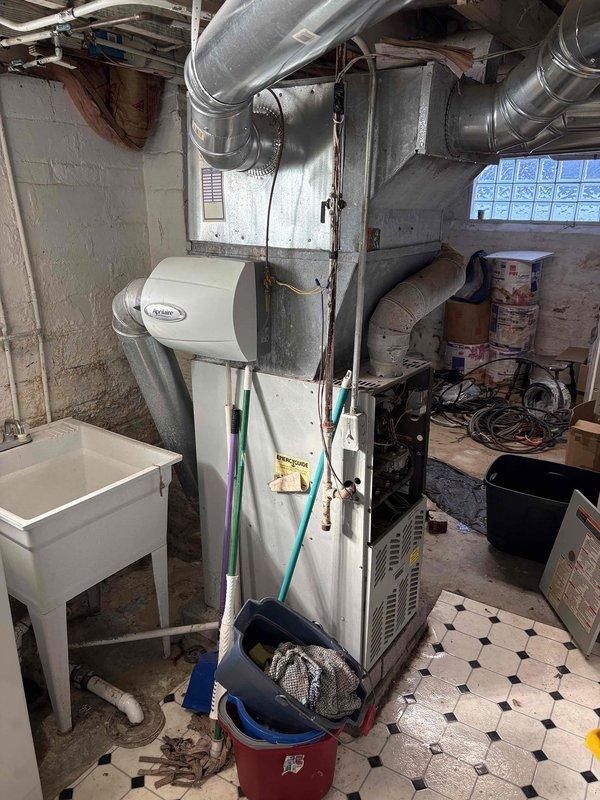 Conducted furnace replacement estimate for aging HVAC system located in basement utility area. Inspected existing Aprilaire humidifier system, ductwork configuration, and electrical service panel to determine compatibility requirements for new equipment. Documented current installation conditions to provide accurate replacement options.