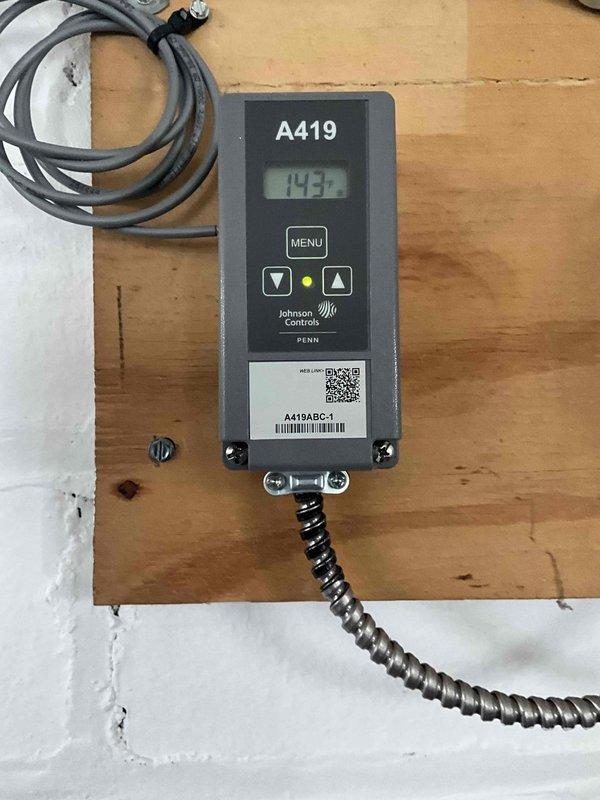 Diagnosed garage heating system with Johnson Controls A419 temperature controller showing readings of 143-164 degrees. Inspected and adjusted controller settings to restore proper heat output on 9-year-old heating unit. Verified system operation and confirmed proper temperature regulation through the digital controller.