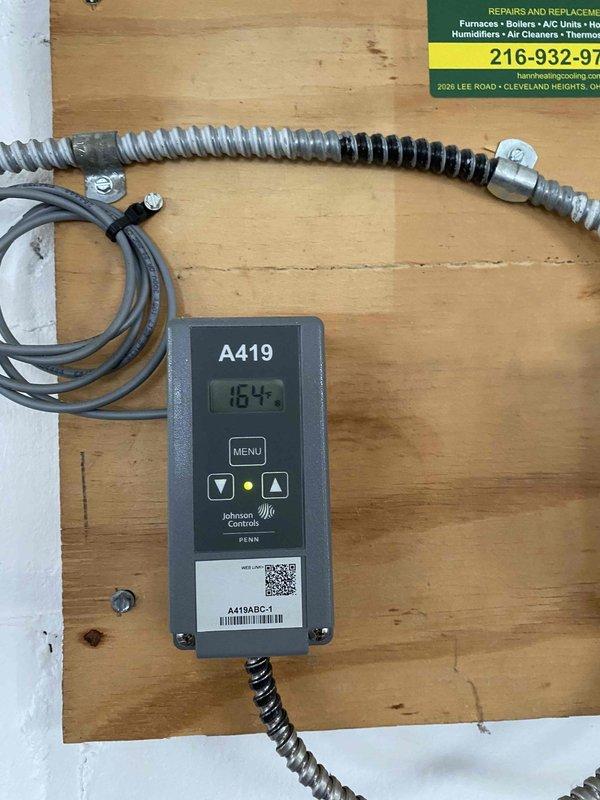 Diagnosed garage heating system with Johnson Controls A419 temperature controller showing readings of 143-164 degrees. Inspected and adjusted controller settings to restore proper heat output on 9-year-old heating unit. Verified system operation and confirmed proper temperature regulation through the digital controller.