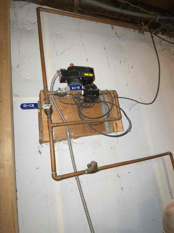 Performed scheduled maintenance on steam boiler system. Inspected circulation pump assembly mounted on wooden backboard and examined Honeywell control box connections. Checked valve operation and inspected copper piping configuration for proper functionality and signs of corrosion.
