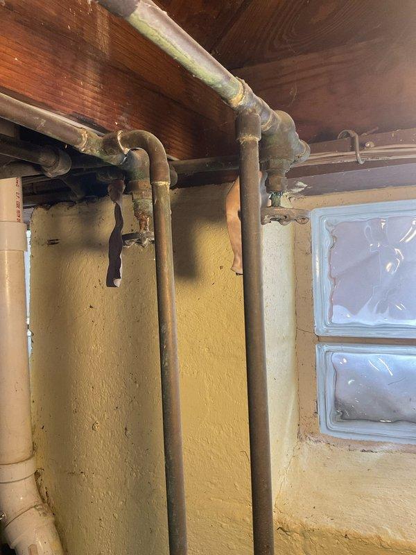 Conducted comprehensive plumbing assessment of aging copper supply line system showing significant oxidation and corrosion, particularly at joints and connection points. Inspection also revealed vertical waste stack with multiple connections in basement area requiring attention. Documented condition of plumbing infrastructure with photographs for future reference and potential remediation planning.