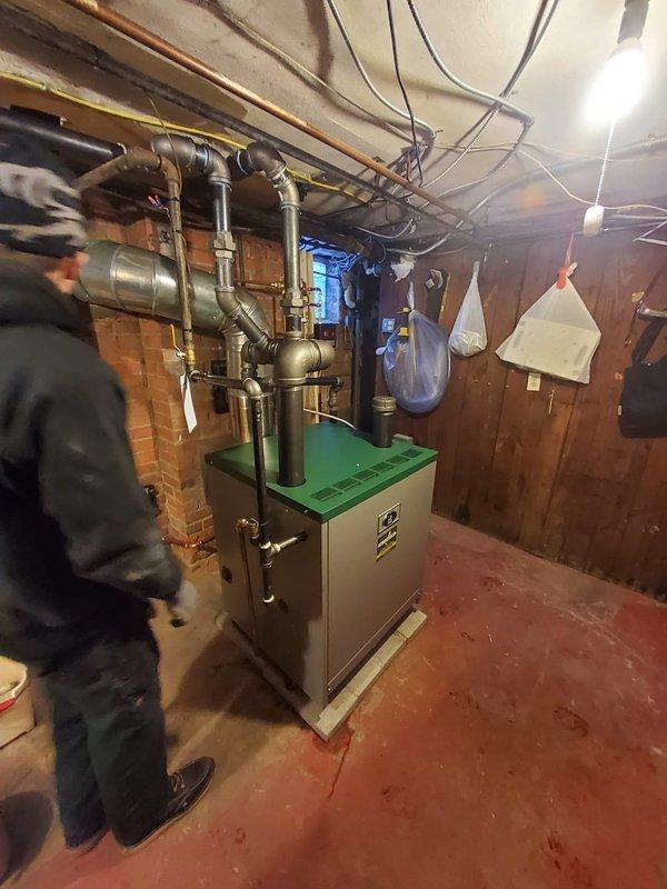 Successfully removed dual steam boilers and installed new Peerless boiler system in basement utility area, complete with new backflow preventer, digital water feeder, low water cut-off, and flue piping. System integration included connection to existing pipe network with proper routing of supply and return lines.
