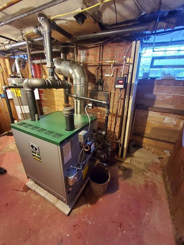 Successfully removed dual steam boilers and installed new Peerless boiler system in basement utility area, complete with new backflow preventer, digital water feeder, low water cut-off, and flue piping. System integration included connection to existing pipe network with proper routing of supply and return lines.