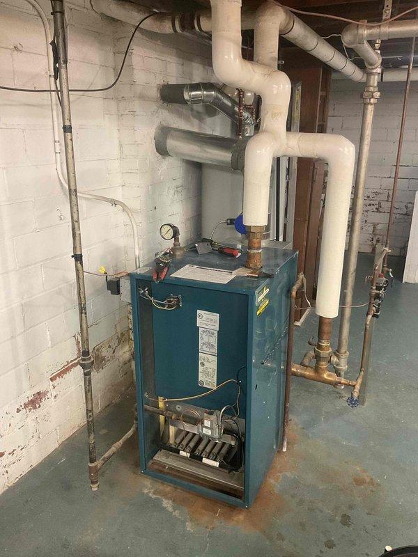 Performed annual heating maintenance on a residential boiler system. Inspected and serviced the burner assembly, checked all connections and valves for proper operation, and verified venting system integrity. No significant issues found in the teal-colored boiler unit or associated components including expansion tank and circulation system.