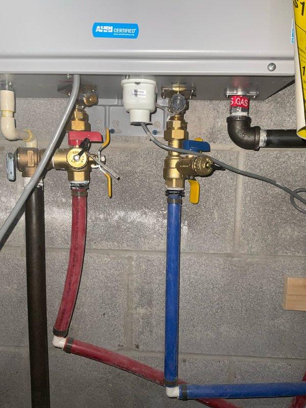 Performed scheduled assessment of tankless water heater system to verify proper operation. Inspected all connections including hot/cold water lines, pressure relief valve, and gas supply line. Examined PEX plumbing runs and drainage pipes in ceiling area; confirmed all components functioning correctly with no leaks or operational issues detected.
