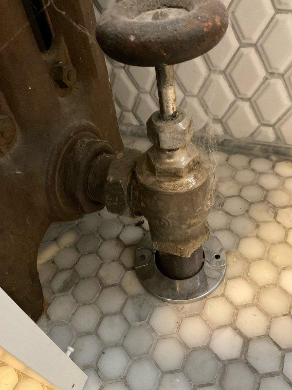 Inspected water damage on 1st and 2nd floor ceilings and identified source as leaking radiator valve. Found aged valve with significant corrosion and mineral buildup, with visible water damage to surrounding wooden floorboards. Recommended replacement of deteriorated valve to prevent further structural damage.