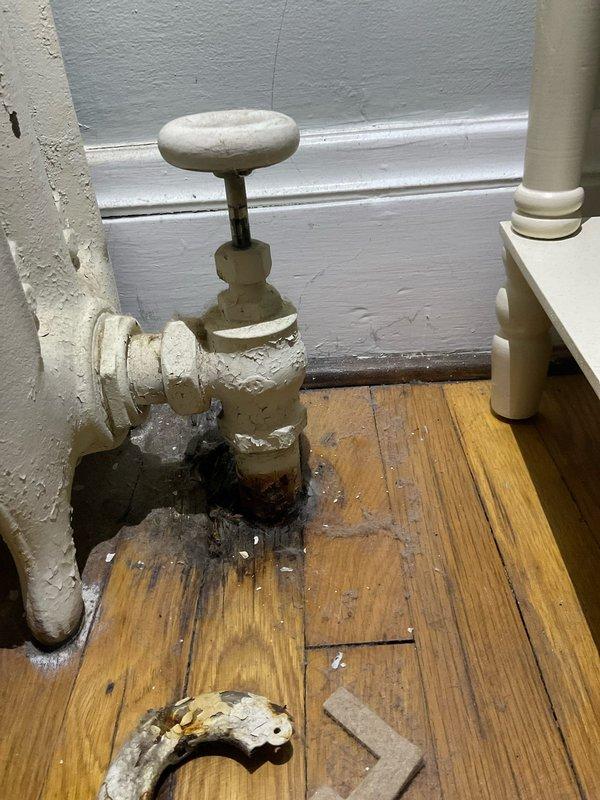Inspected water damage on 1st and 2nd floor ceilings and identified source as leaking radiator valve. Found aged valve with significant corrosion and mineral buildup, with visible water damage to surrounding wooden floorboards. Recommended replacement of deteriorated valve to prevent further structural damage.