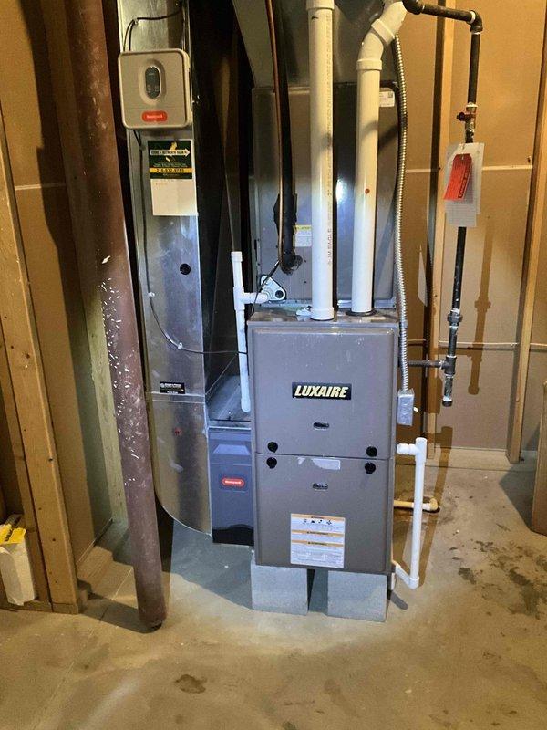 Performed second opinion inspection on Luxaire furnace system with suspected heat exchanger failure. Visual examination confirmed heat exchanger deterioration requiring full replacement. System is currently installed in basement utility area with existing PVC ventilation and drainage components. Noted water staining beneath unit, suggesting possible condensate drainage issues that would need addressing during replacement.