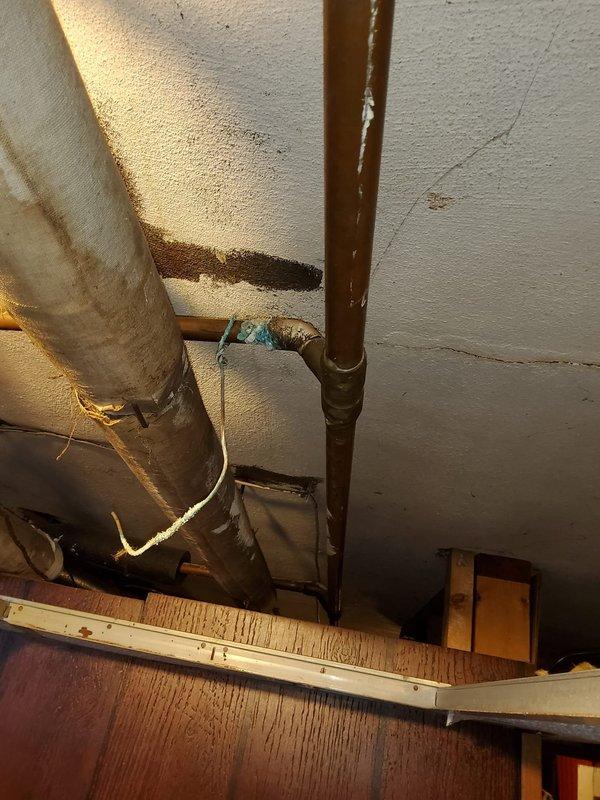 Inspected leaking stack behind recently installed boiler. Observed significant corrosion and water damage at connection points of cast iron waste pipe and copper supply lines. Documented evidence of ceiling water staining and pipe deterioration, recommending complete replacement of affected section to prevent further leakage and structural damage.