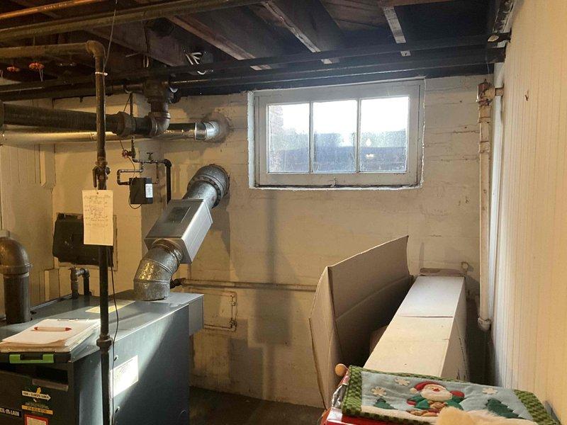 Conducted comprehensive evaluation of steam boiler system with severely compromised heat exchanger, exhibiting significant damage on both sides. Documentation of basement utility room revealed exposed ductwork, control systems, and plumbing infrastructure with visible corrosion at connection points, particularly in the brass valve assembly.