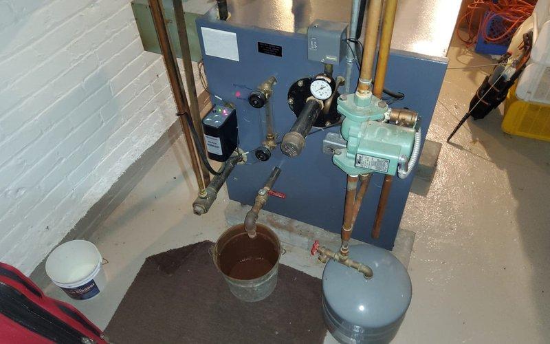Conducted scheduled preventive maintenance on residential steam boiler system. Inspected pressure gauge readings, checked all copper lines and connections for leaks, and verified proper operation of expansion vessel. Placed collection bucket under minor condensate drip point for temporary containment while servicing the system.