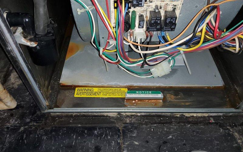 Performed diagnostic inspection on furnace with reported water leak. Identified severe rust and corrosion on internal metal bracket, likely source of the leak. Inspection of control panel revealed possible moisture intrusion with visible corrosion along housing edges. Previous blower motor replacement by technician Derek L. noted.