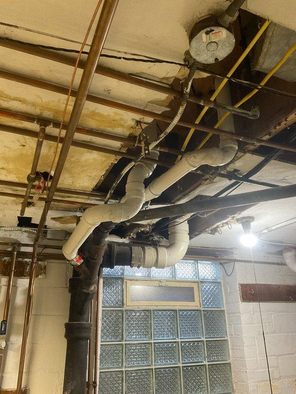 Completed comprehensive kitchen and bathroom sink repiping project, requiring removal of wall access panels to replace deteriorated supply and drainage components. Successfully installed new PVC drain lines and copper supply piping throughout both locations, addressing visible water damage in the utility area ceiling and ensuring proper connections to existing plumbing infrastructure.
