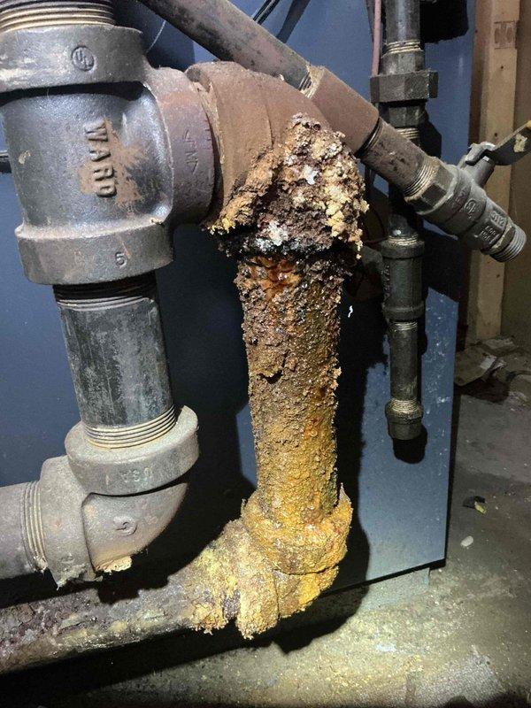 Responded to service call for boiler pipe leak. Upon inspection, identified severe corrosion and mineral buildup on vertical pipe section, particularly concentrated at 90-degree elbow joint. Replaced deteriorated pipe sections and associated fittings to resolve the active leak and prevent future failure.