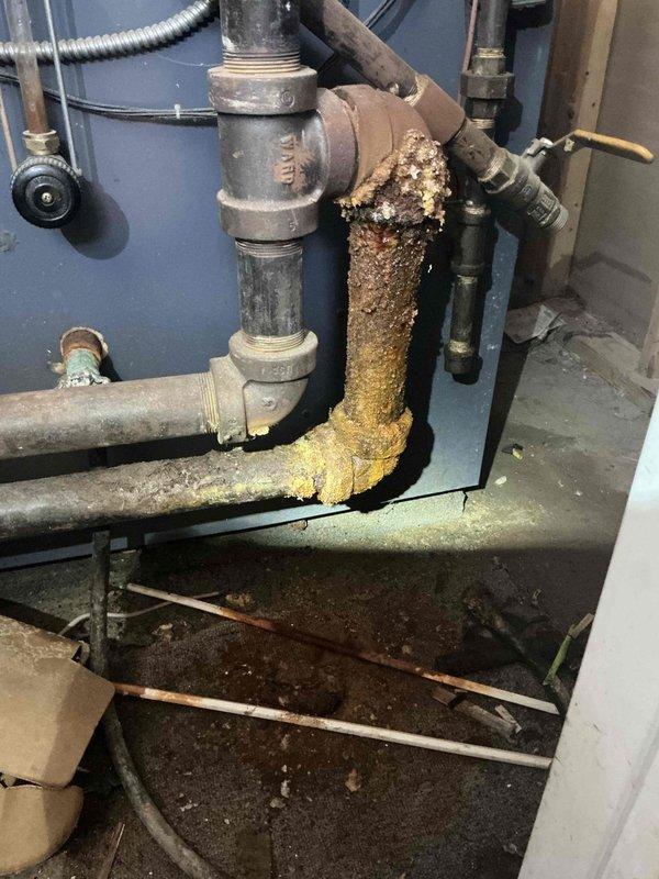 Responded to service call for boiler pipe leak. Upon inspection, identified severe corrosion and mineral buildup on vertical pipe section, particularly concentrated at 90-degree elbow joint. Replaced deteriorated pipe sections and associated fittings to resolve the active leak and prevent future failure.