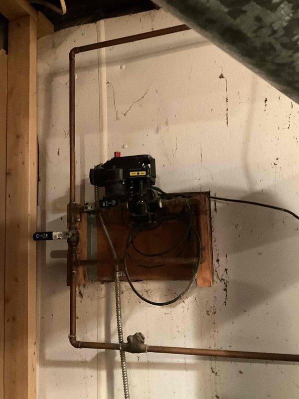 Conducted boiler assessment in residential basement. Inspected existing furnace system with associated ductwork, noting condition of galvanized metal ventilation components and connections. Evaluated circulation pump mounted on wall with connected copper piping for integration with heating infrastructure.
