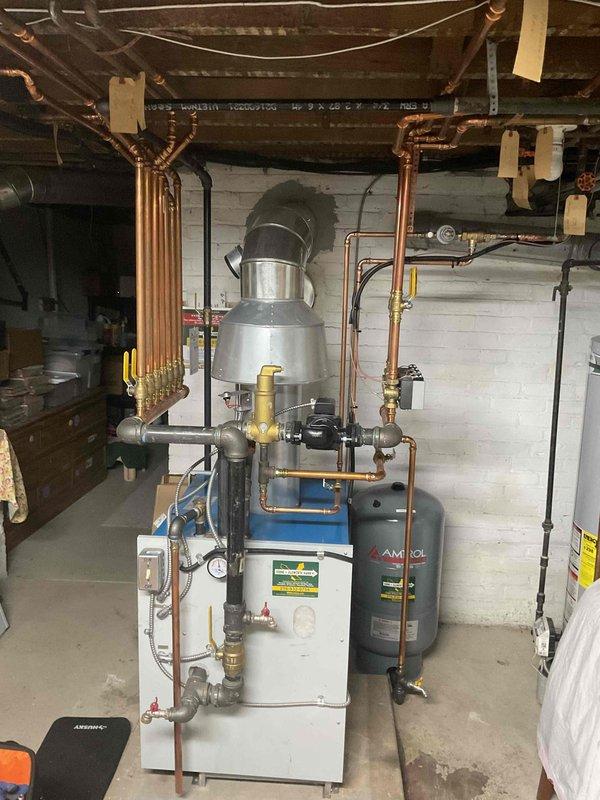Completed annual inspection of 3-year-old boiler system under Natural Home Plan. Inspected expansion tank, copper piping network, valves, and fittings throughout the basement utility area. Verified proper operation of heating components and documented condition with photos of the main boiler unit and associated mechanical equipment.