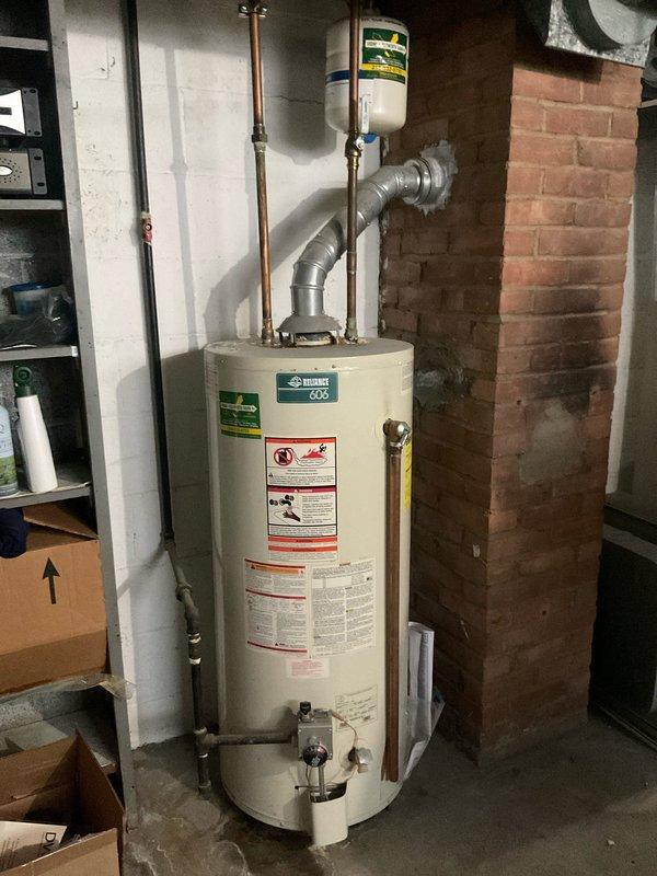 Diagnosed and repaired leaking Bradford White tanked water heater in 50-year-old residential property. Identified leak source at bottom connection point, replaced deteriorated fittings and installed new expansion tank to prevent future pressure issues. Confirmed proper venting of exhaust system and verified all connections were secure with no further leakage detected during testing.