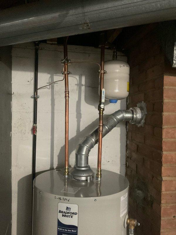 Diagnosed and repaired leaking Bradford White tanked water heater in 50-year-old residential property. Identified leak source at bottom connection point, replaced deteriorated fittings and installed new expansion tank to prevent future pressure issues. Confirmed proper venting of exhaust system and verified all connections were secure with no further leakage detected during testing.